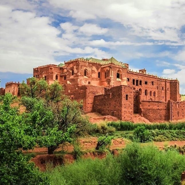 Kasbah Taourirt surrounded by palm trees in Ouarzazate, Morocco